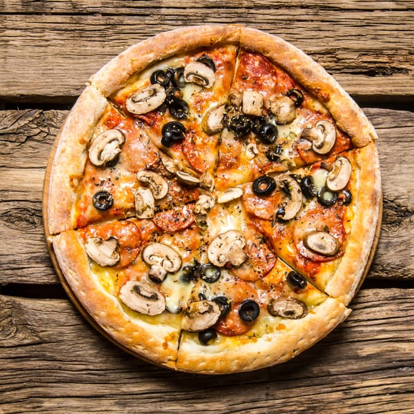 Angelo's Pizza House pizza with mushrooms, black olives, and pepperoni on a wooden table.